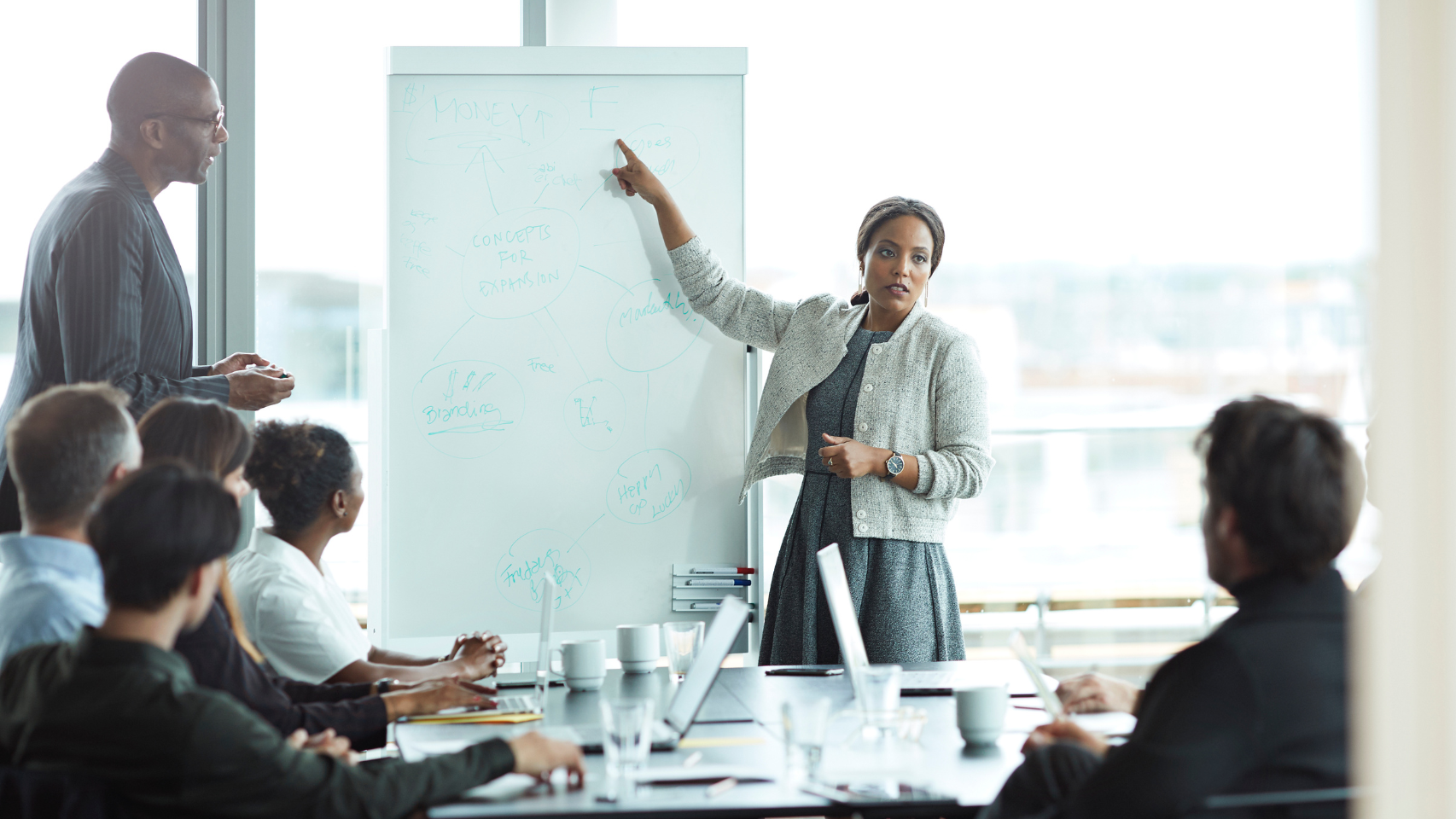 Woman lawyer standing in front of a white board presenting in a meeting.