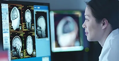 Doctor in a dark room reading an xray on a computer screen