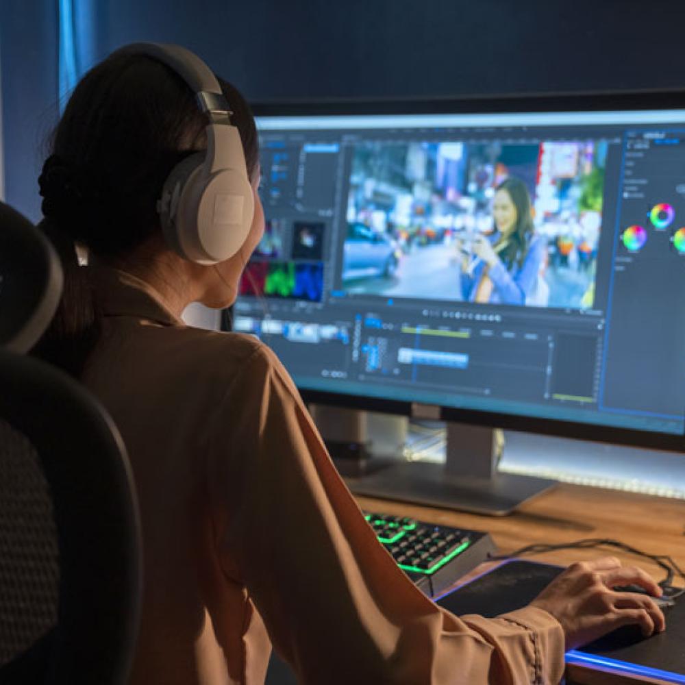 A woman editing video on a desktop computer